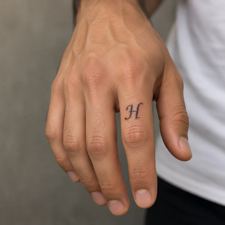 H Letter tattoo on man hand