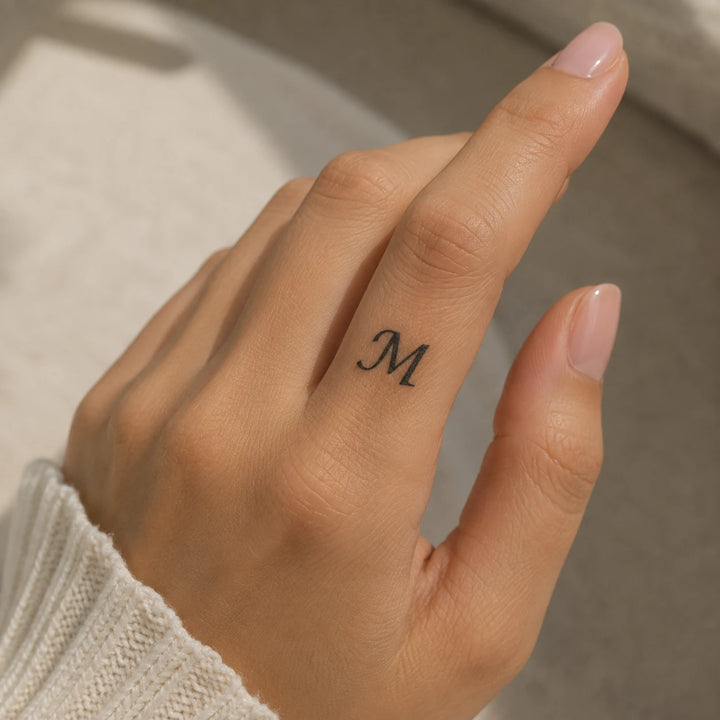 M Letter Tattoo on womans hand