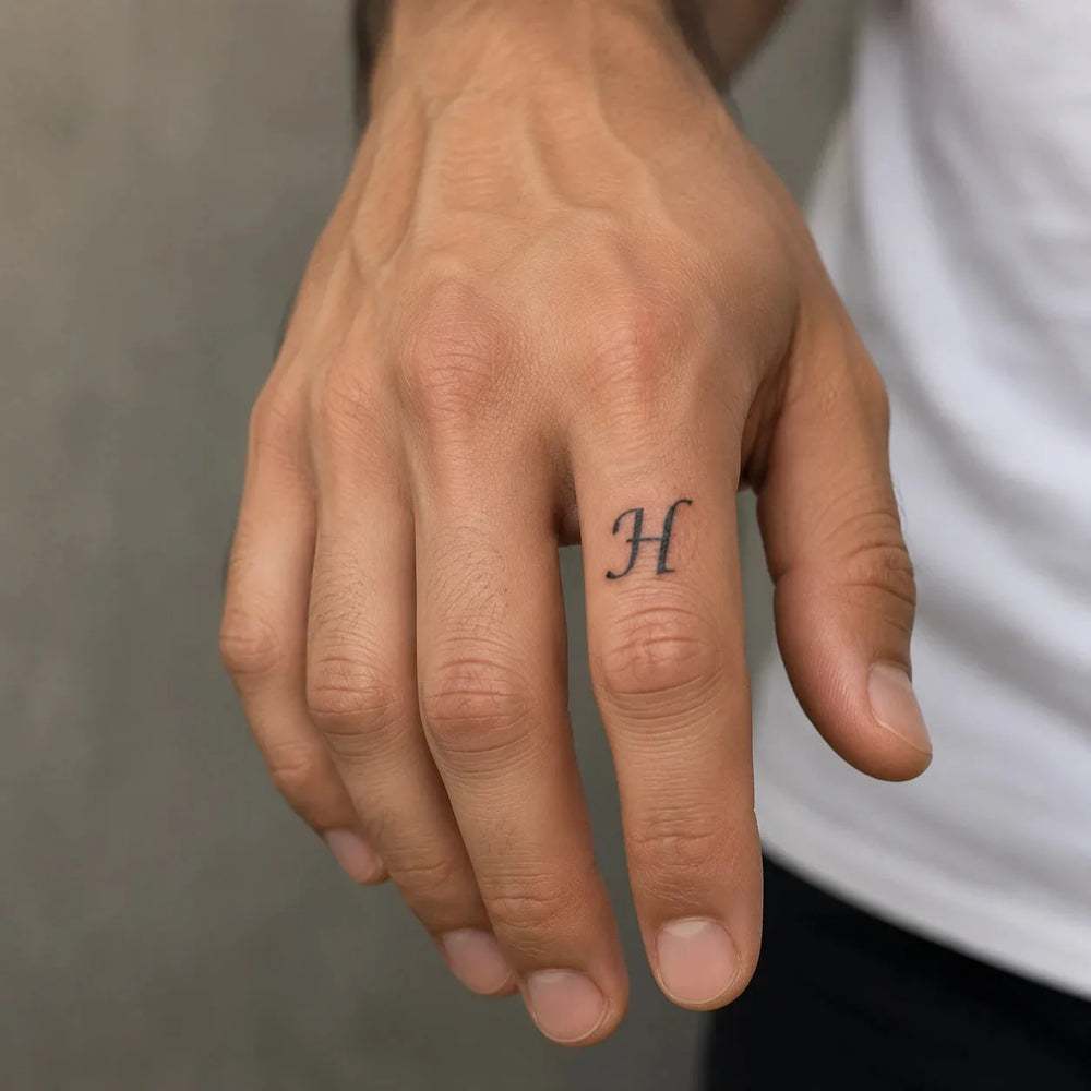H Letter tattoo on man hand